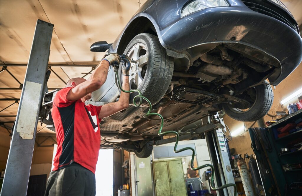 Mechanic, worker, repairman changing wheels of car in garage.